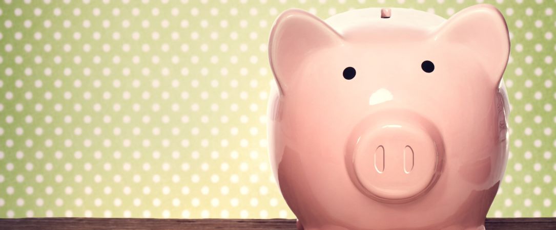 rosafarbenes Sparschwein aus Porzellan vor pünktchen Tapete